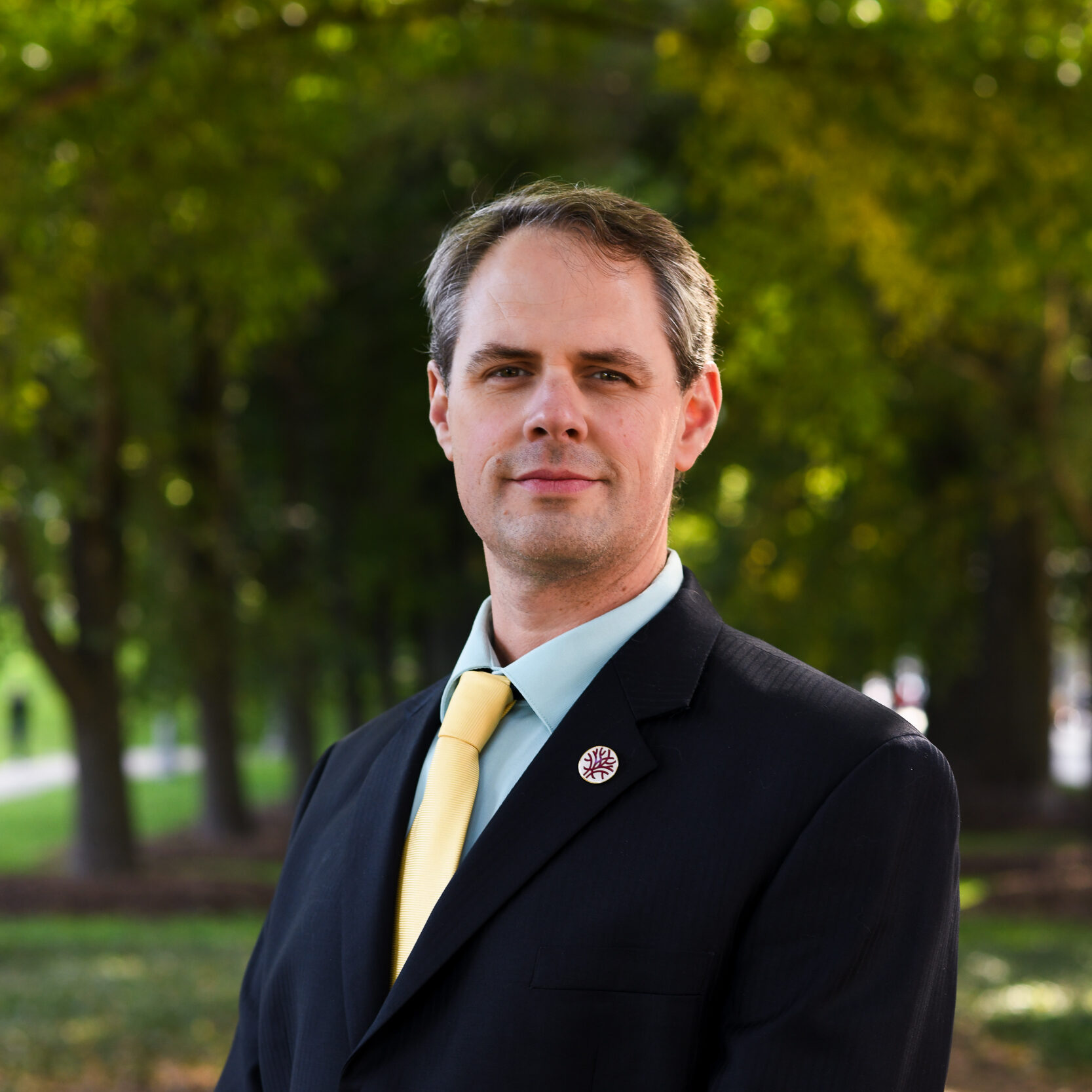 a man in a suit and tie standing in a park